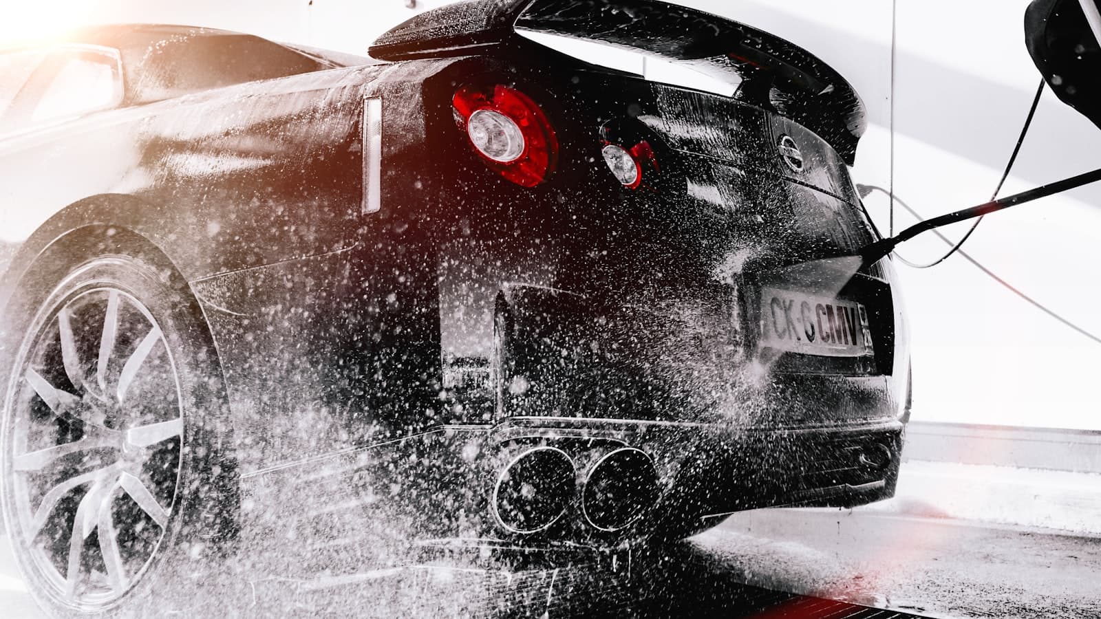 Pressure rinse blasting foam off a black sports car