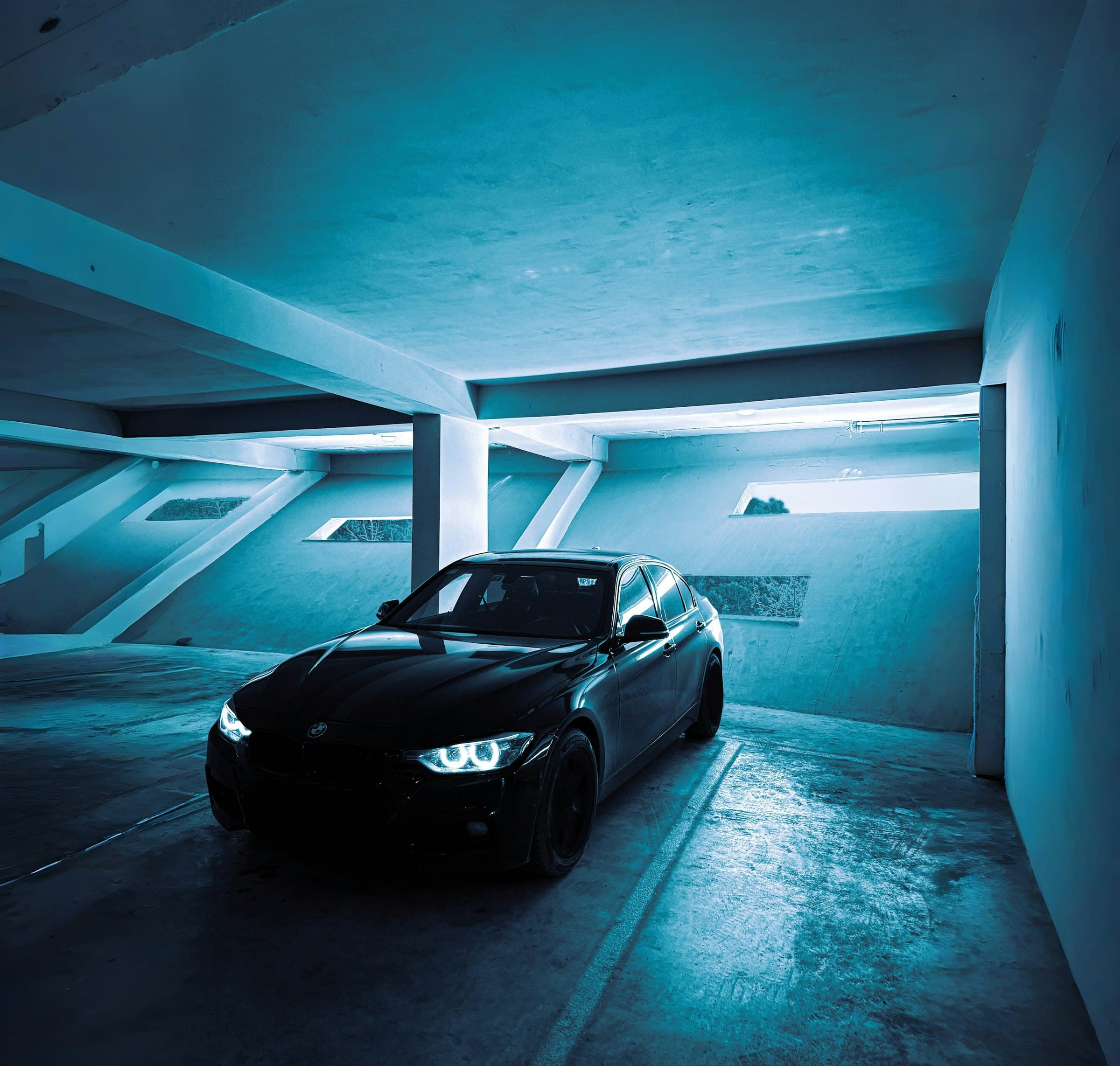 Black sedan parked in a blue-lit garage at night