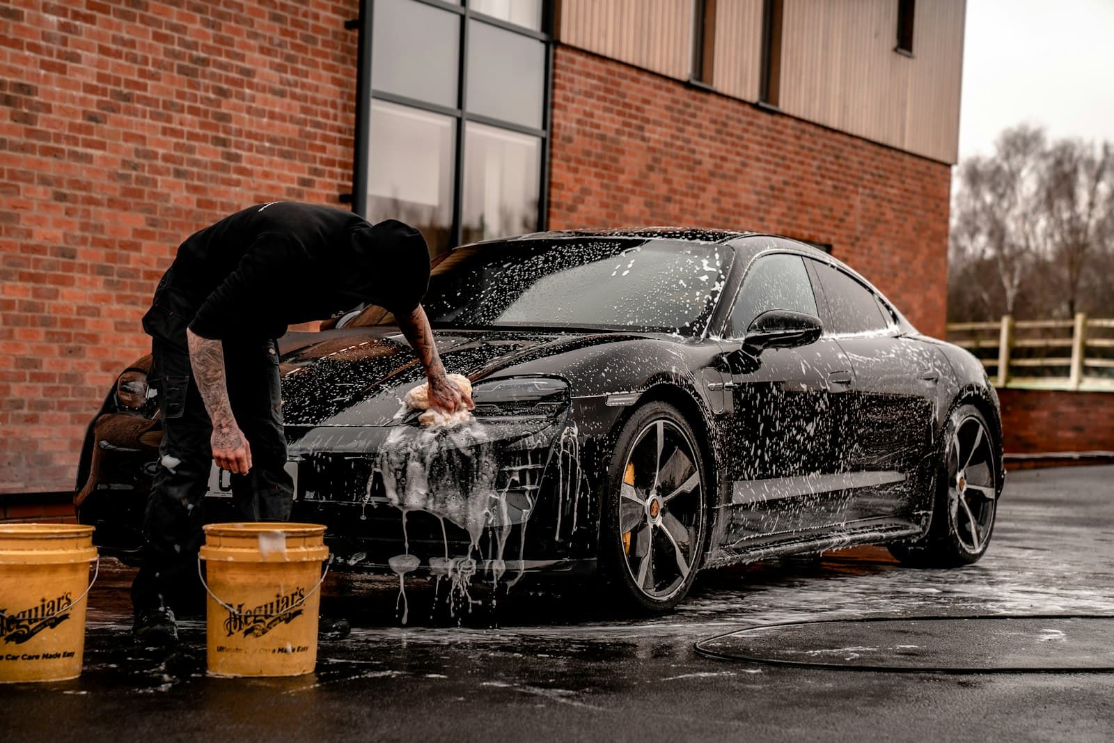 Hand washing a black car with thick suds and a wash mitt